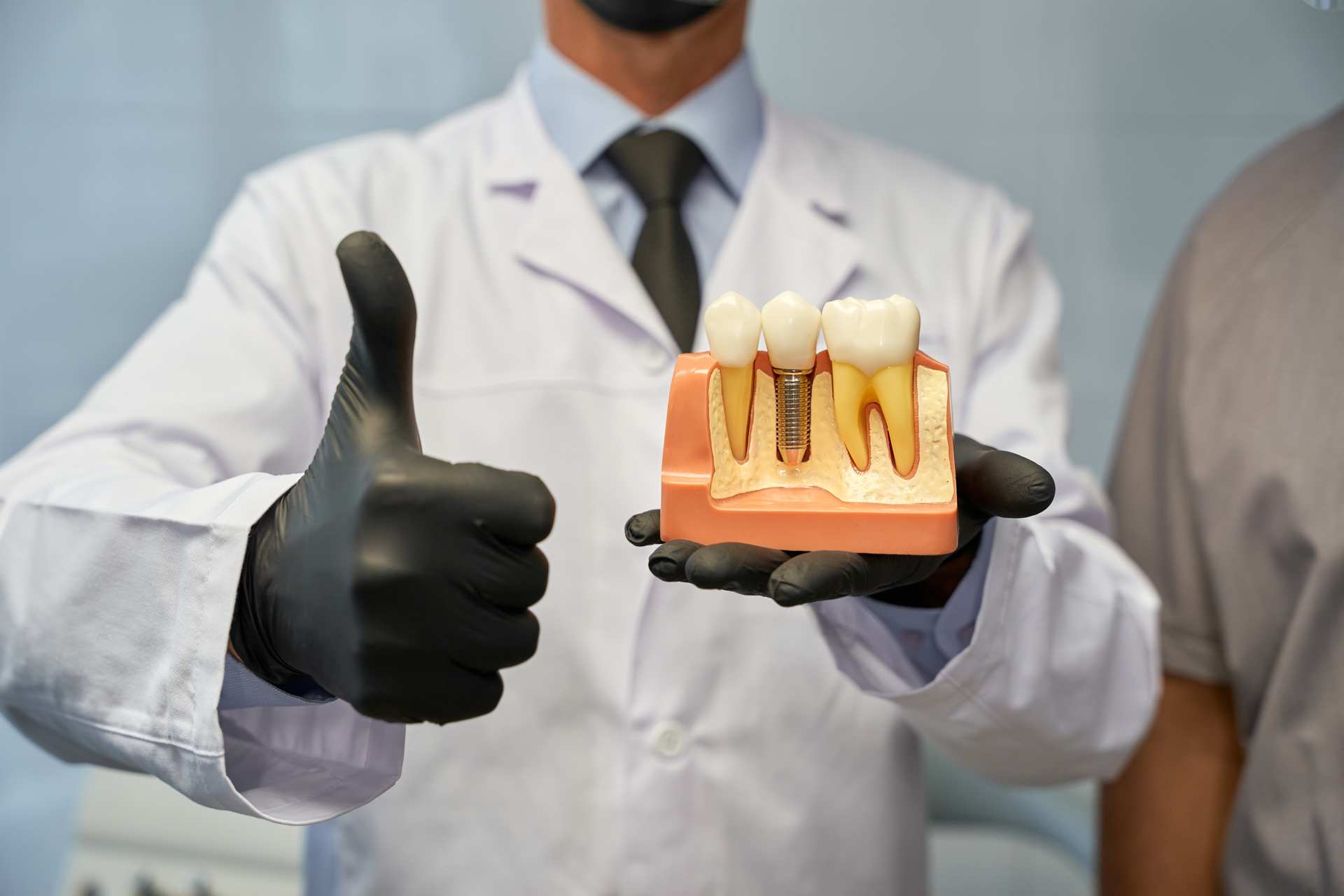 01 Dental technician with a dental prosthesis in hand saying OK