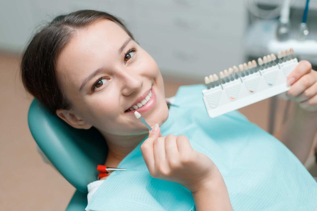 02 A young woman choosing a color sample for her teeth whitening treatment.