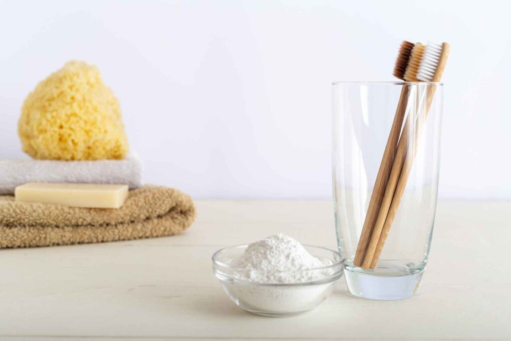 03 Toothbrushes made of bamboo together with a bowl of baking soda for use as a home tooth whitener.