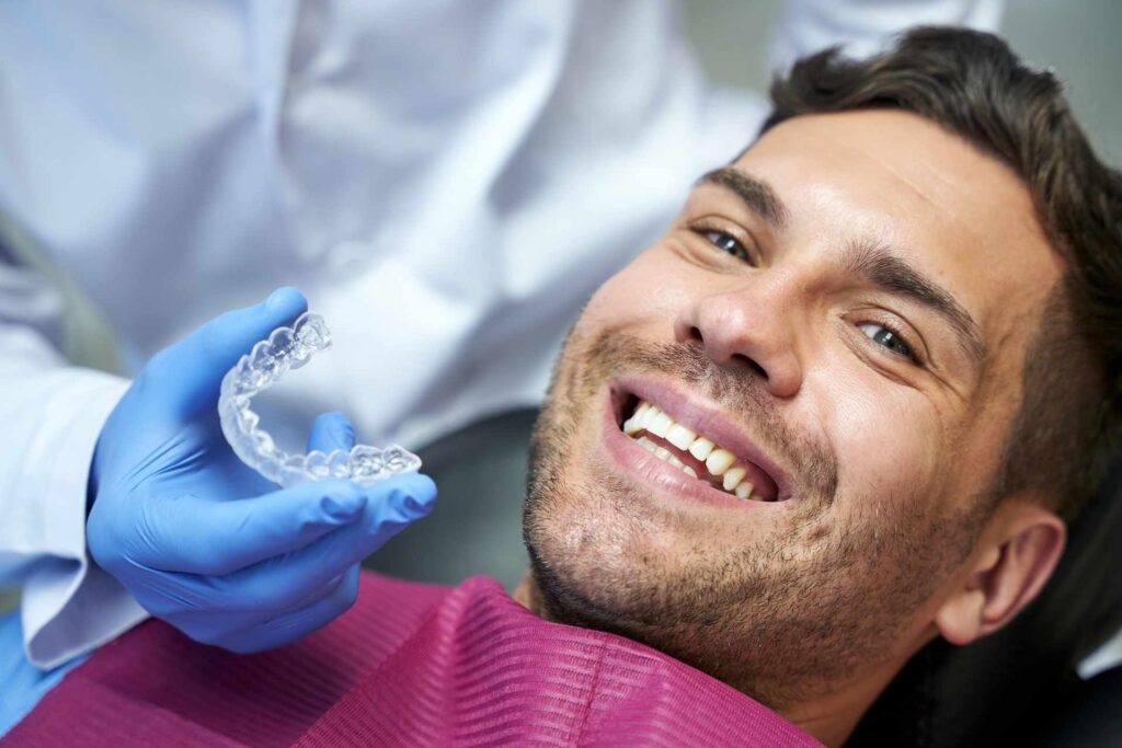 05 A smiling man before a teeth whitening treatment with a splint and gel.