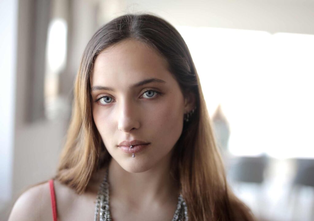 02 Closeup of a young girl with a lower lip piercing, one of the causes of receding gums on a single tooth.