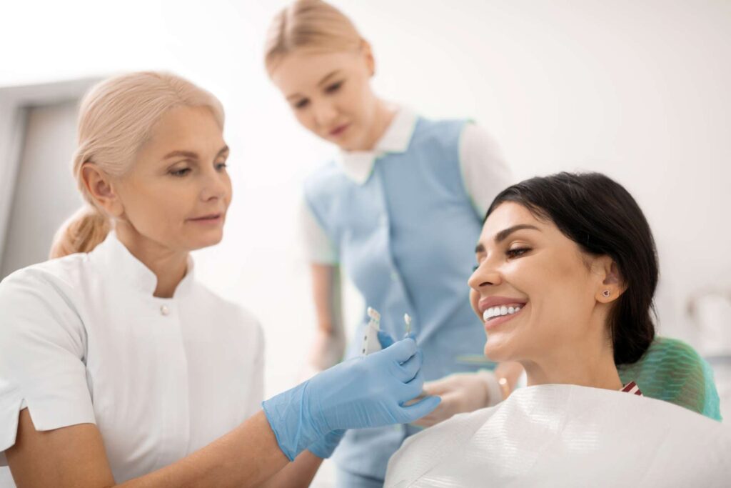 A dentist and nurse take samples of the color of a patient's teeth in the clinic for porcelain veneers.