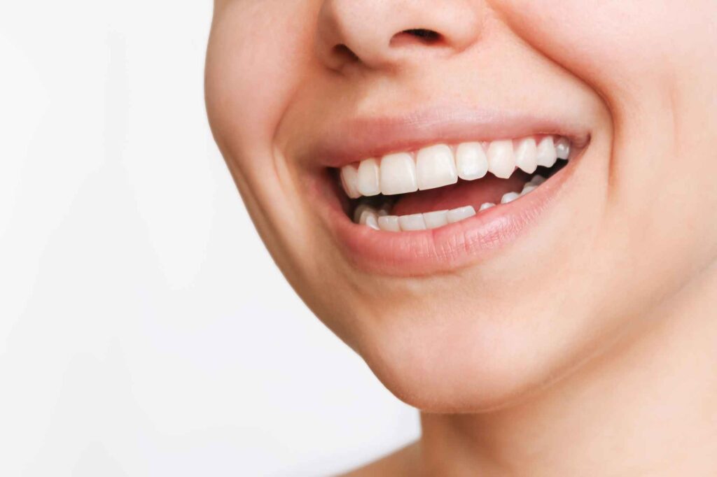 05 Detail of a woman smiling on a light neutral background.