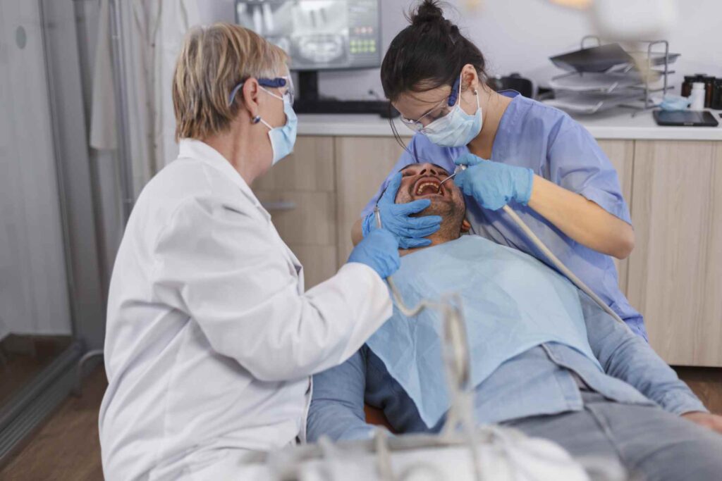 03 Dentist and her assistant giving dental treatment to a patient in the clinic_How long after dental implants can I eat nor