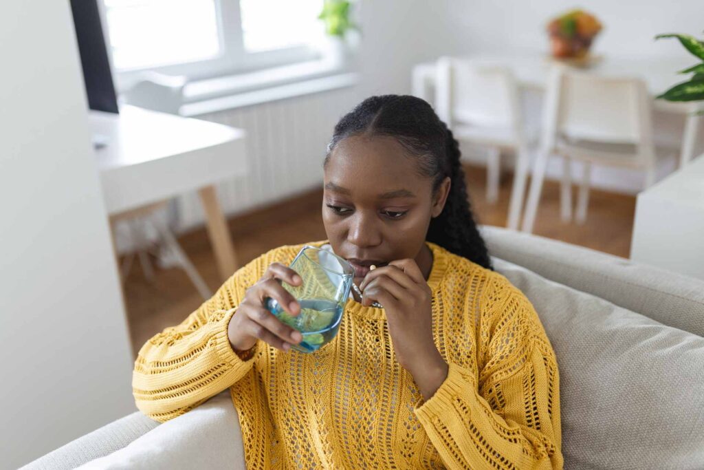 07 A woman taking a drug with a glass of water_Do dental implants hurt