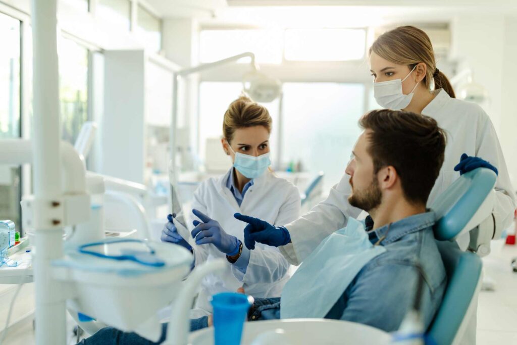 09 Dentist talking to a patient while examining an x-ray film in the clinic_Dental implants pros and cons, dental implants in Miami