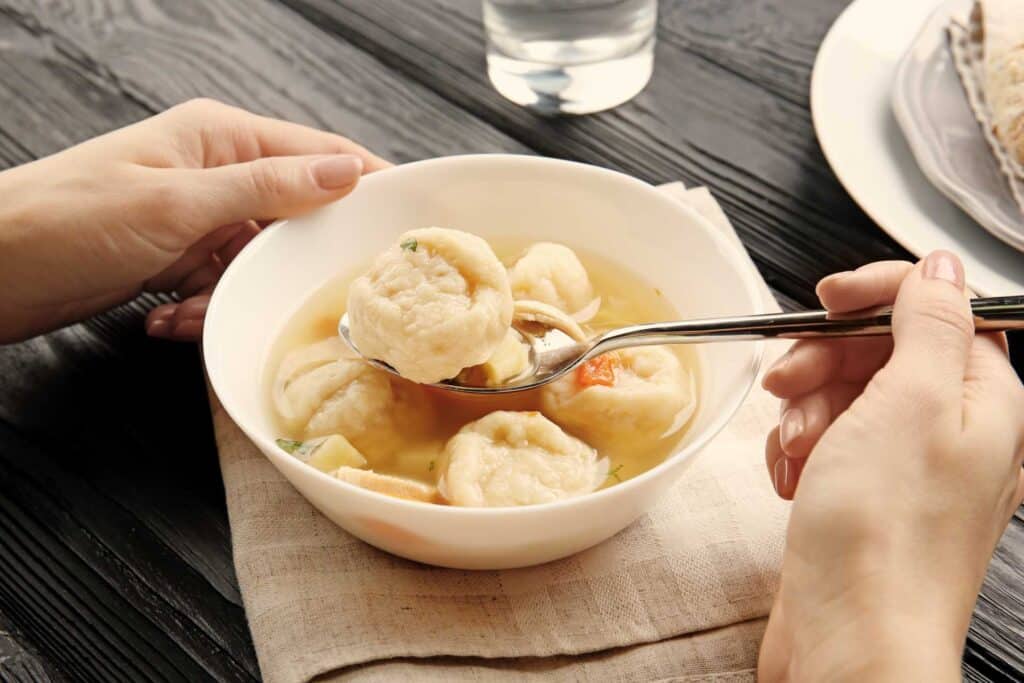 08 Female diner having a broth with chicken meat and dumplings