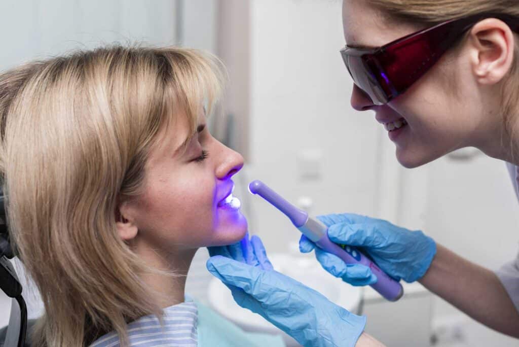 Dentist performing teeth whitening on a patient using light zoom_tooth