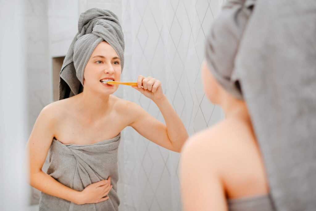 Woman in towels brushing her teeth after showering_tooth