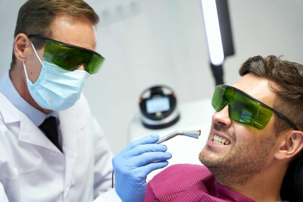 Patient and dentist wearing green safety goggles during laser treatment